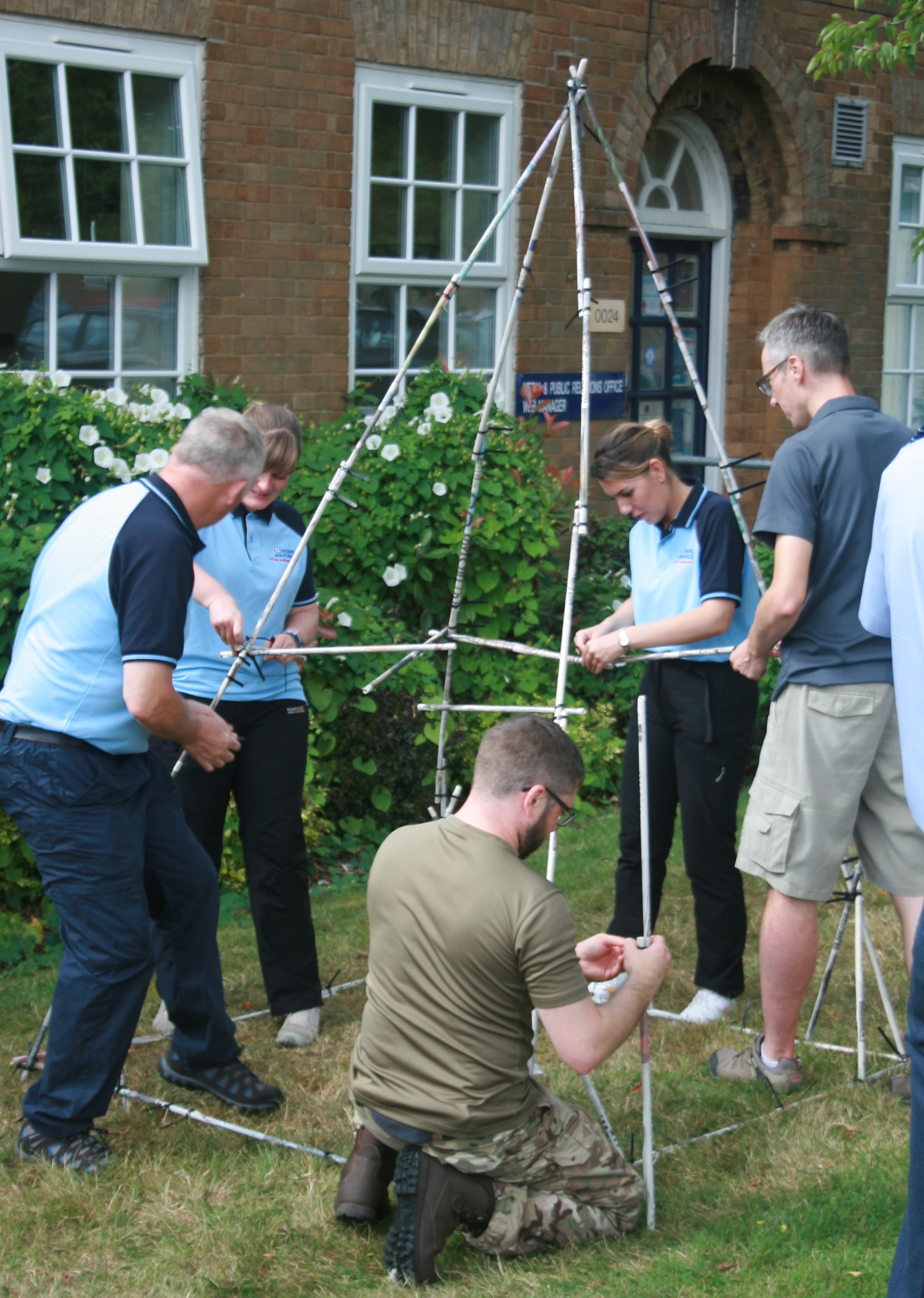 Personnel work to erect a handmade tent frame. 